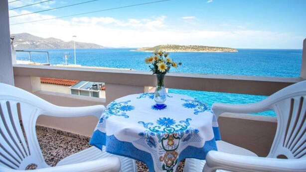 A balcony with a table set for two, overlooking a coastal view. - Pension Mylos (Agios Nikolaos)