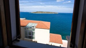 A coastal view from a window overlooking a building with a red-tiled roof and a glass door. - Pension Mylos (Agios Nikolaos)