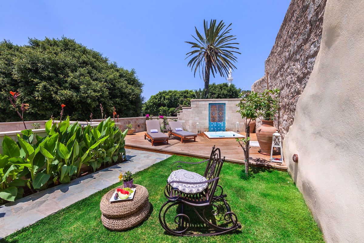 A patio with a rocking chair, lounge chairs, and a small table with a fruit plate.