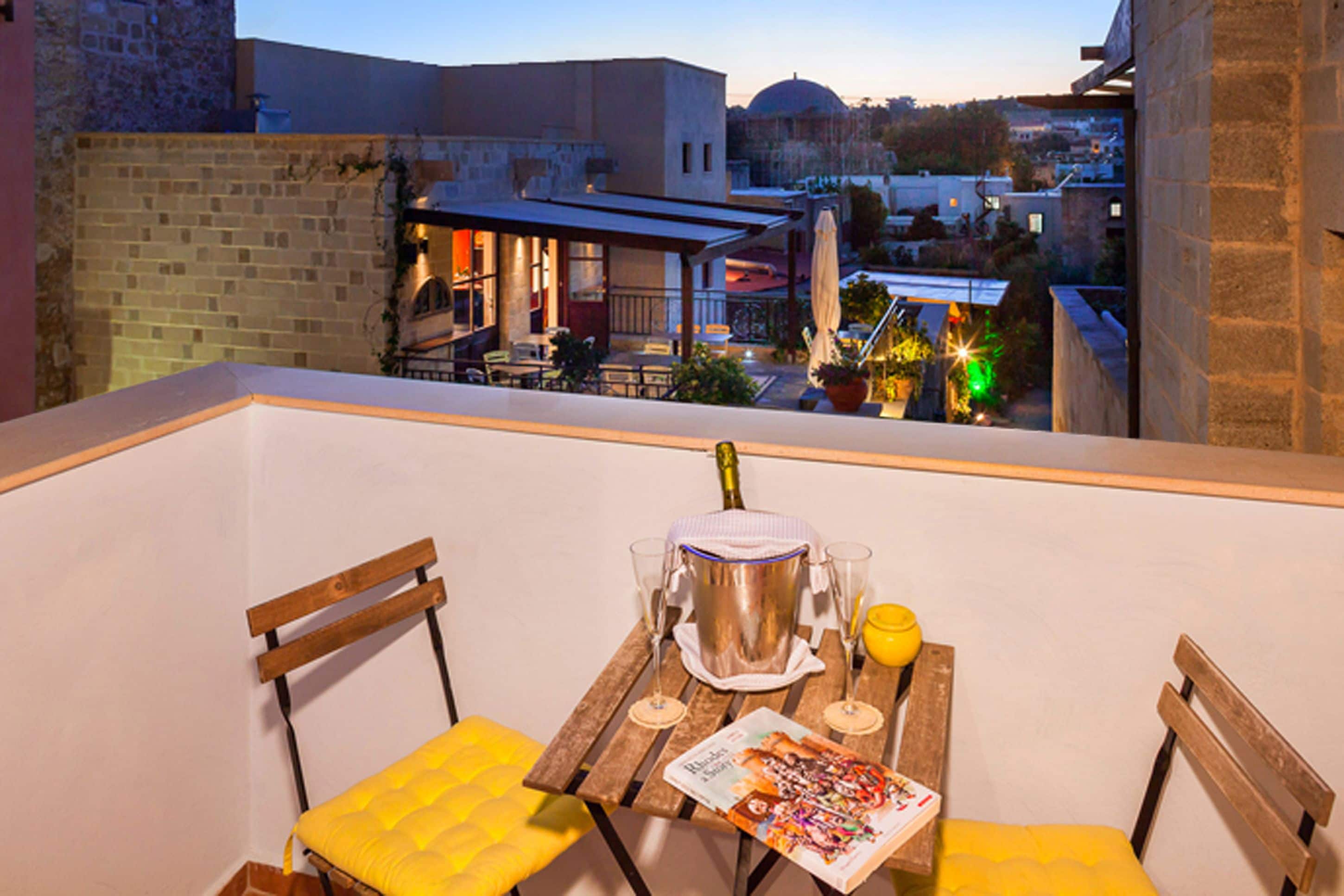 A balcony with a table set for two, a bottle of champagne, and a magazine.