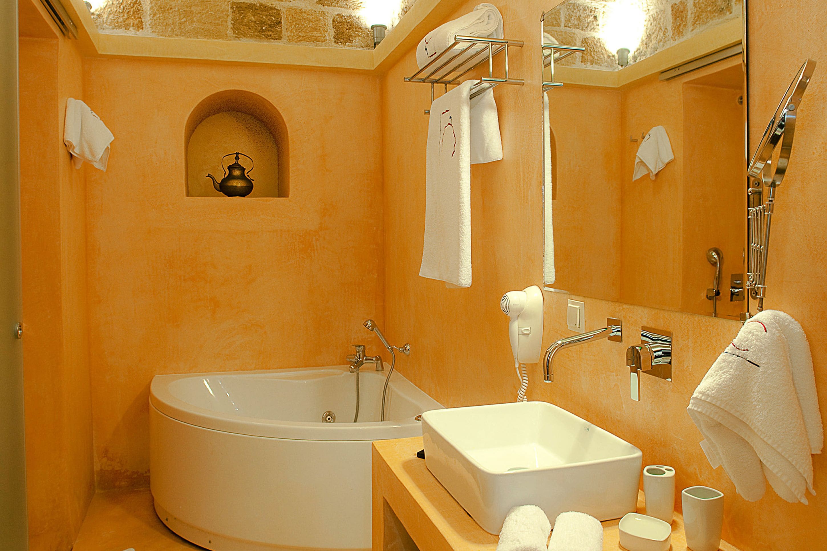 Een badkamer met een bad, een wastafel en een douche. Er liggen handdoeken en een haardroger op het aanrecht.