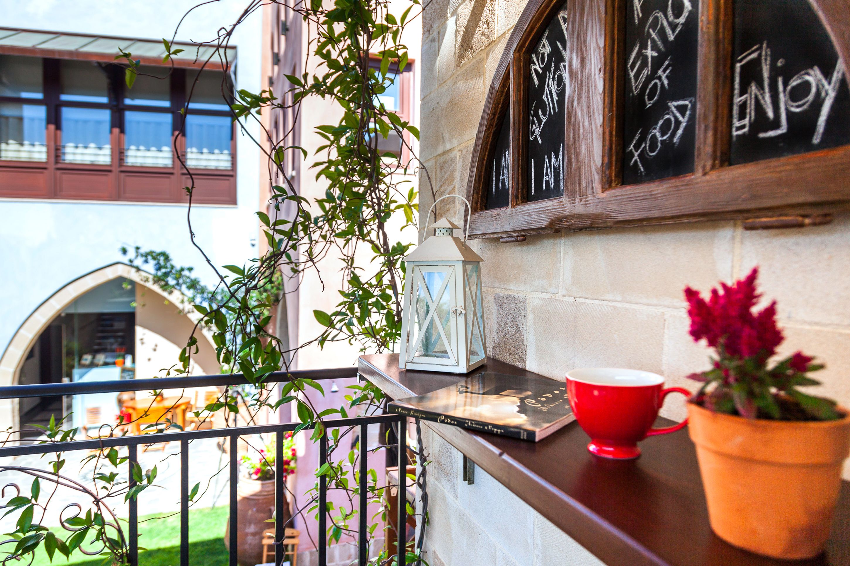 A balcony with a red cup, a lantern, and a potted plant.