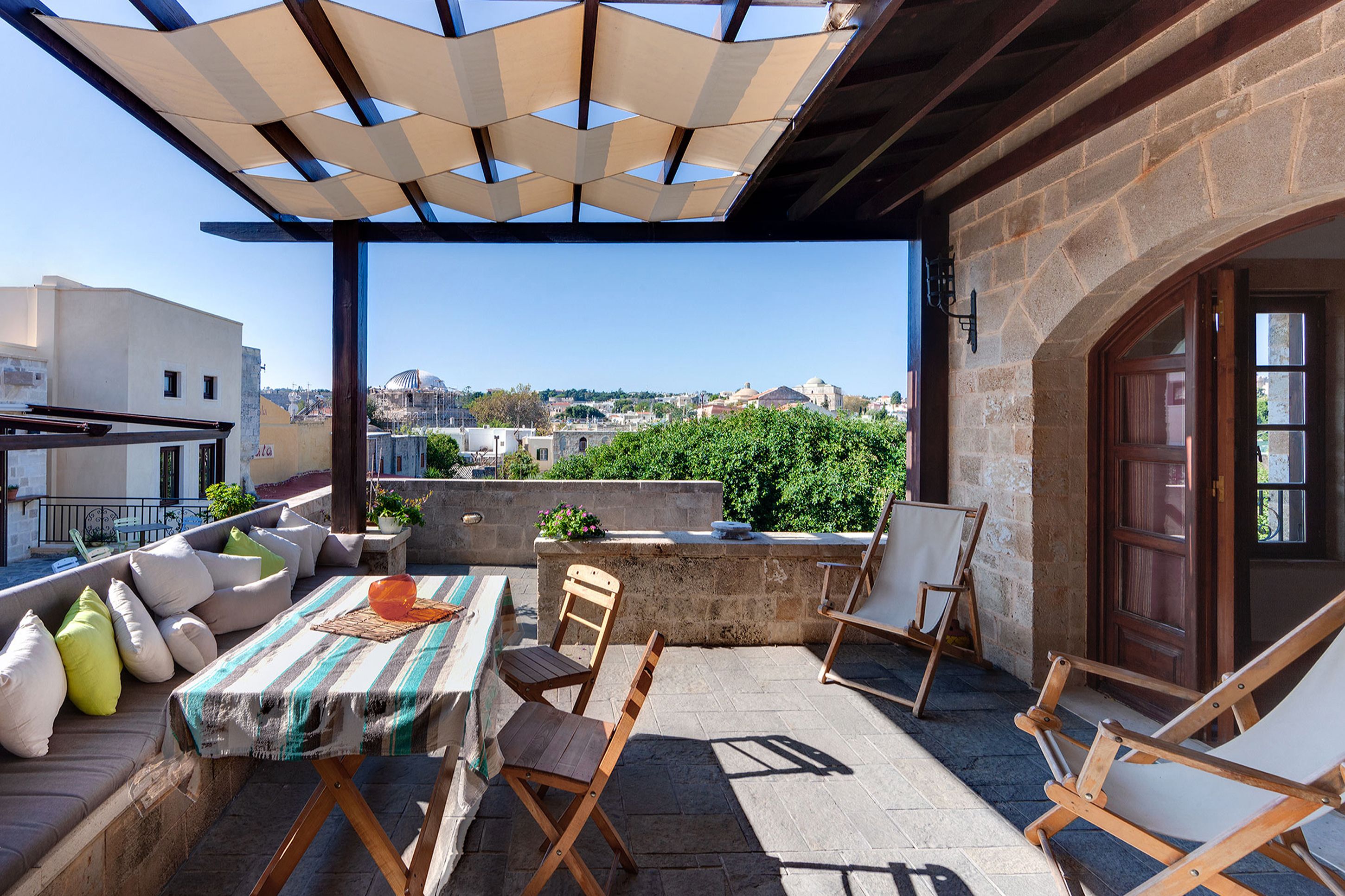 An outdoor patio with a table, chairs, and a view of the city.