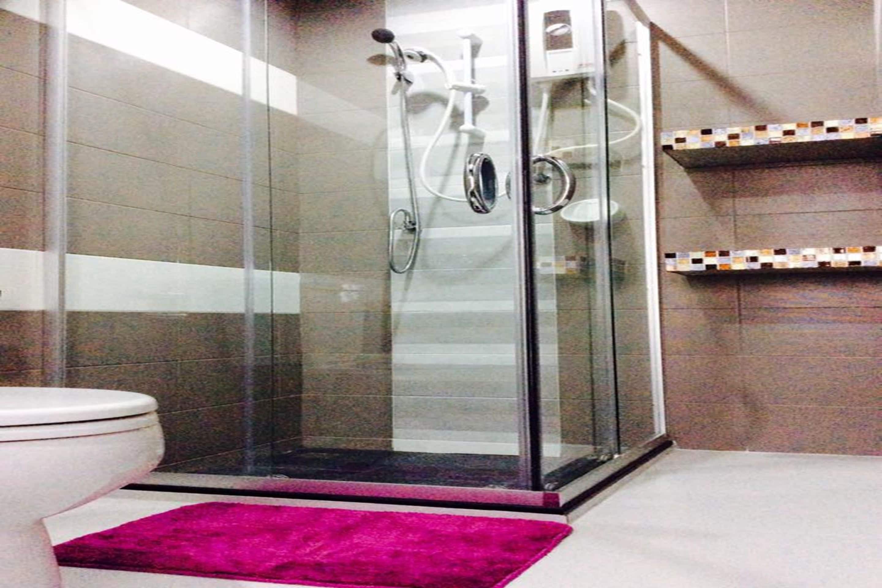 Un baño con ducha acristalada, inodoro y paredes con azulejos.