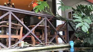 A koi pond with a wooden bridge, surrounded by indoor seating and potted plants. - EZ House & Cafe (Sukhothai)