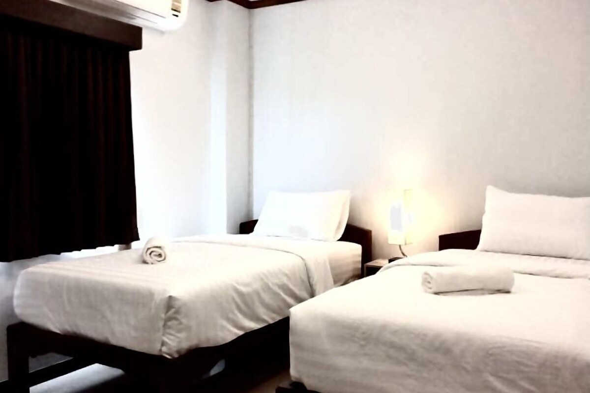 Une chambre d’hôtel avec deux lits, une table de chevet, une lampe et un appareil de climatisation.