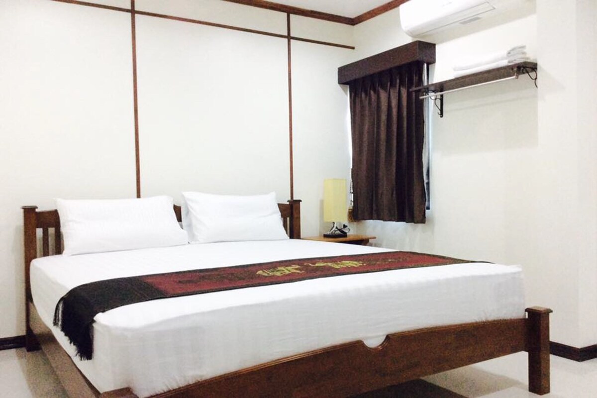 Une chambre d’hôtel standard, équipée d’un lit simple, d’une table de chevet, d’une lampe et d’un appareil de climatisation.