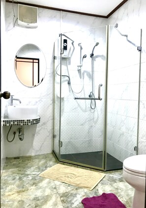 Un baño con cabina de ducha de vidrio, lavabo con espejo e inodoro.