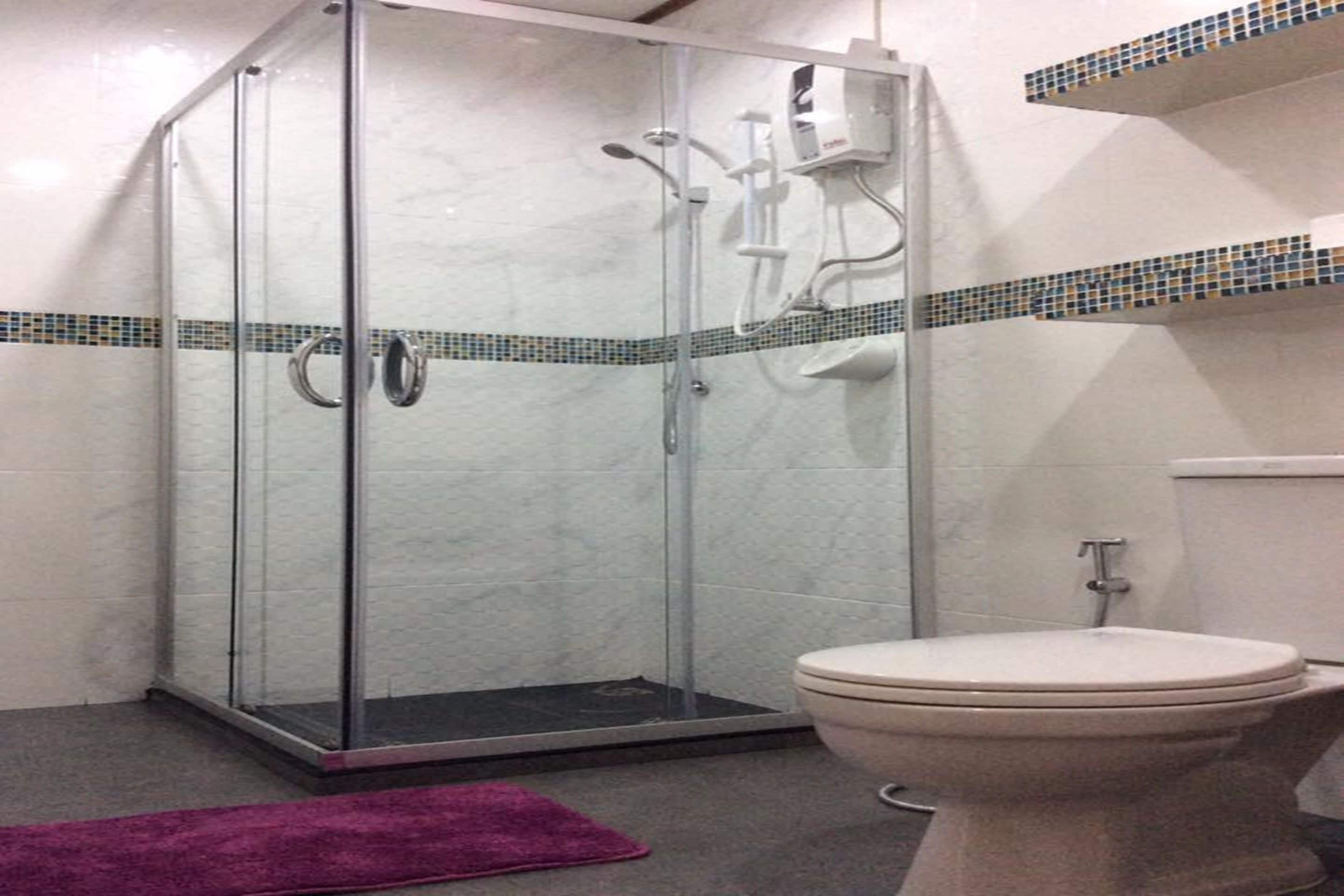 A bathroom with a glass-enclosed shower, a toilet, and a tiled backsplash.