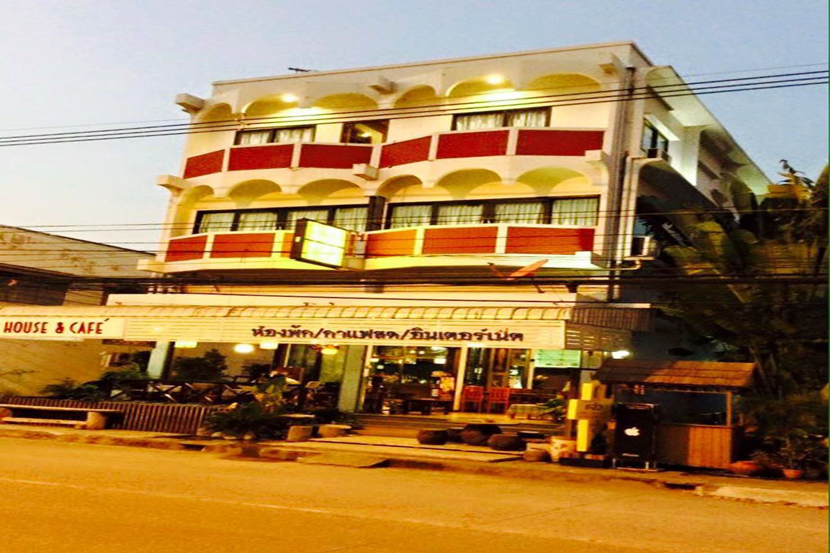 A multi-story building with a 'House & Cafe' sign, featuring balconies and a ground-level seating area.