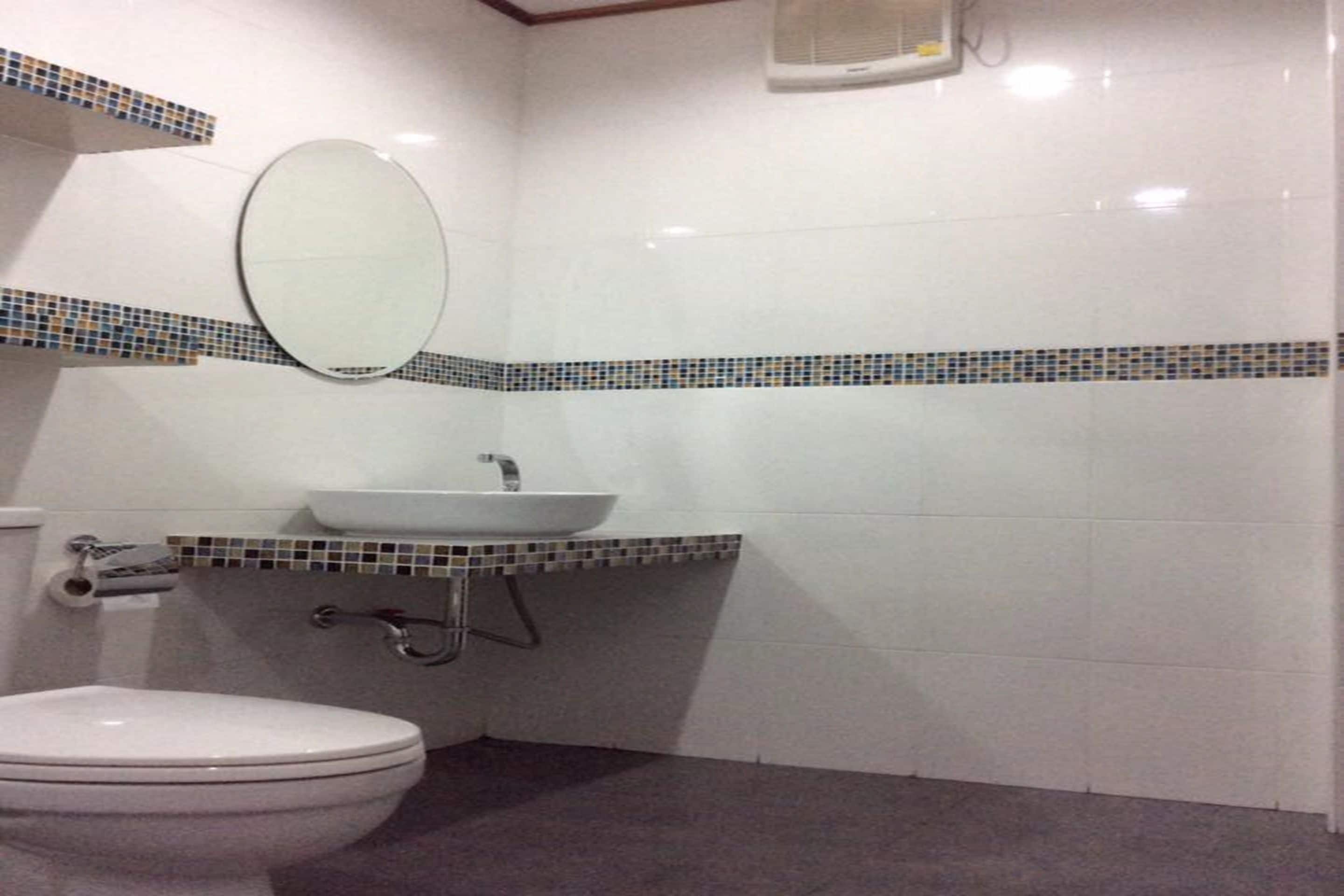 A bathroom with a toilet, sink, and mirror.