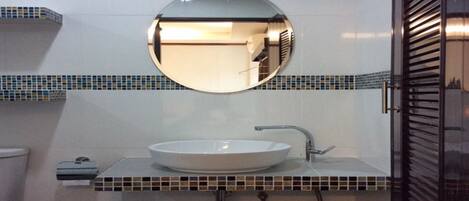 A bathroom with a round mirror, a white sink, and a tiled backsplash.