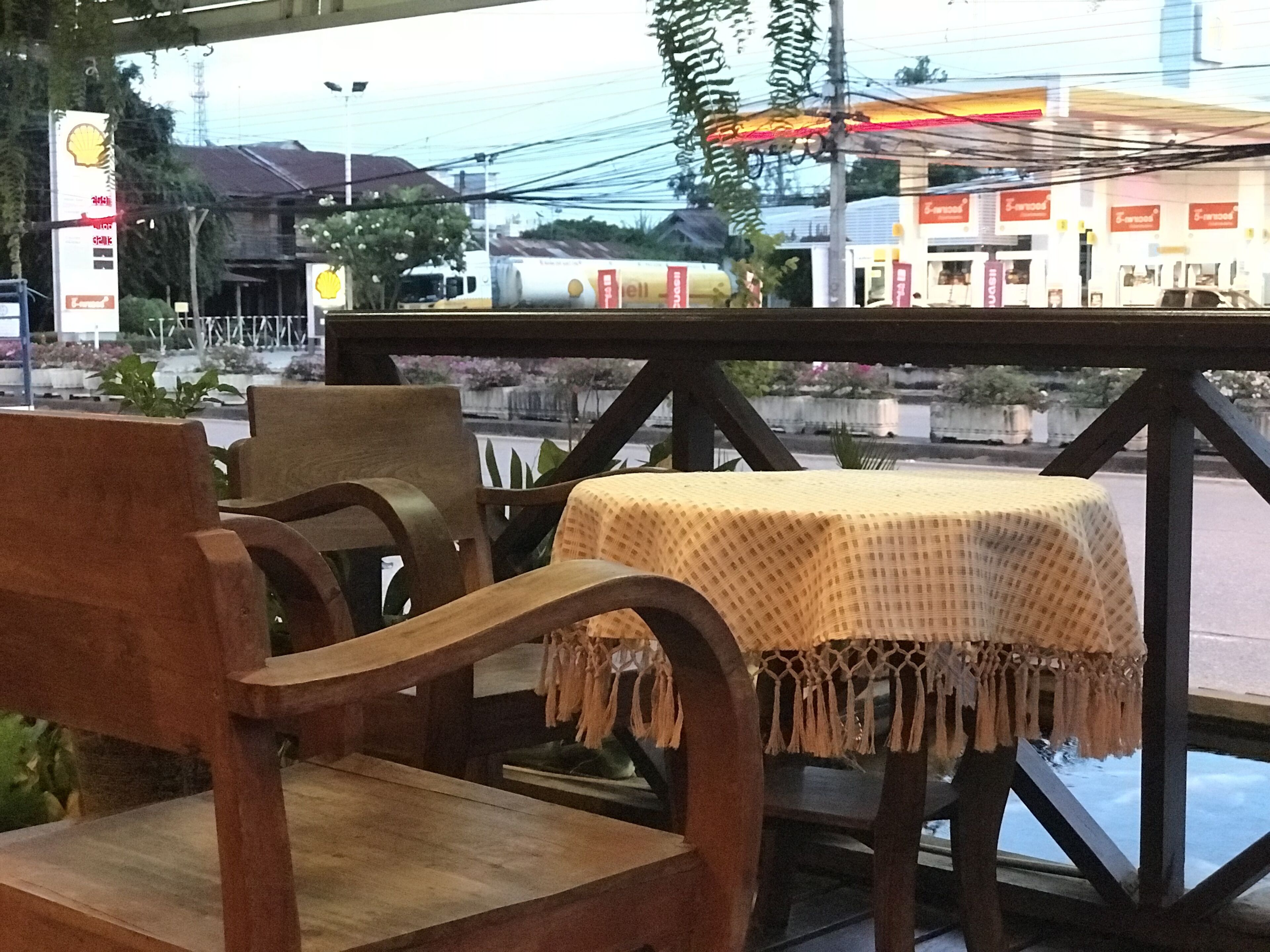 A wooden chair and table set outdoors with a view of a street and buildings in the background.