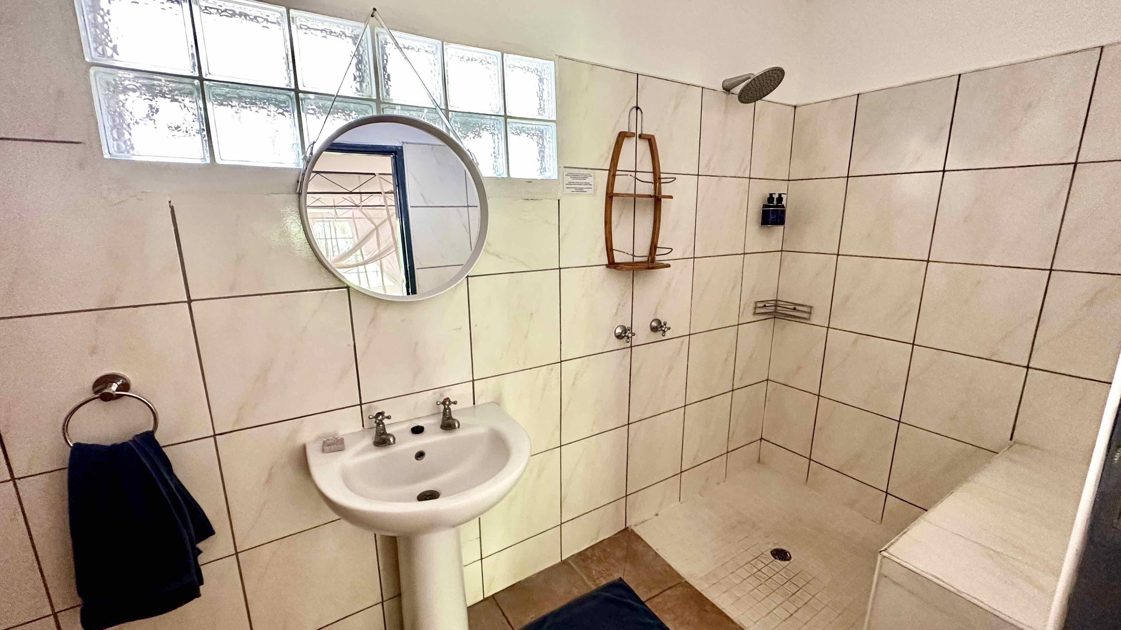 Un baño con lavamanos, espejo, ducha y paredes de azulejos.