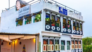 A multi-story building with a sign for 'Cafe Helsinki' and a 'Rooms' sign. - Hotel Hanuman Ghat (Udaipur)