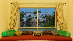 A room with a large window overlooking a cityscape. - Hotel Hanuman Ghat (Udaipur)