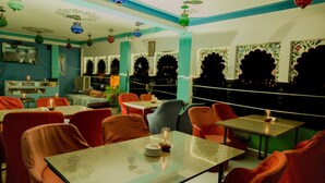 A restaurant with a cozy interior, featuring tables and chairs arranged for dining. - Hotel Hanuman Ghat (Udaipur)