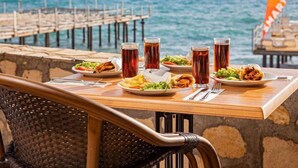 Een gedekte tafel met eten en drinken in een restaurant aan zee, met uitzicht op de oceaan.