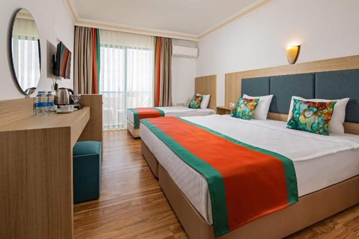 A hotel room with two beds, a desk, a mirror, and a TV.