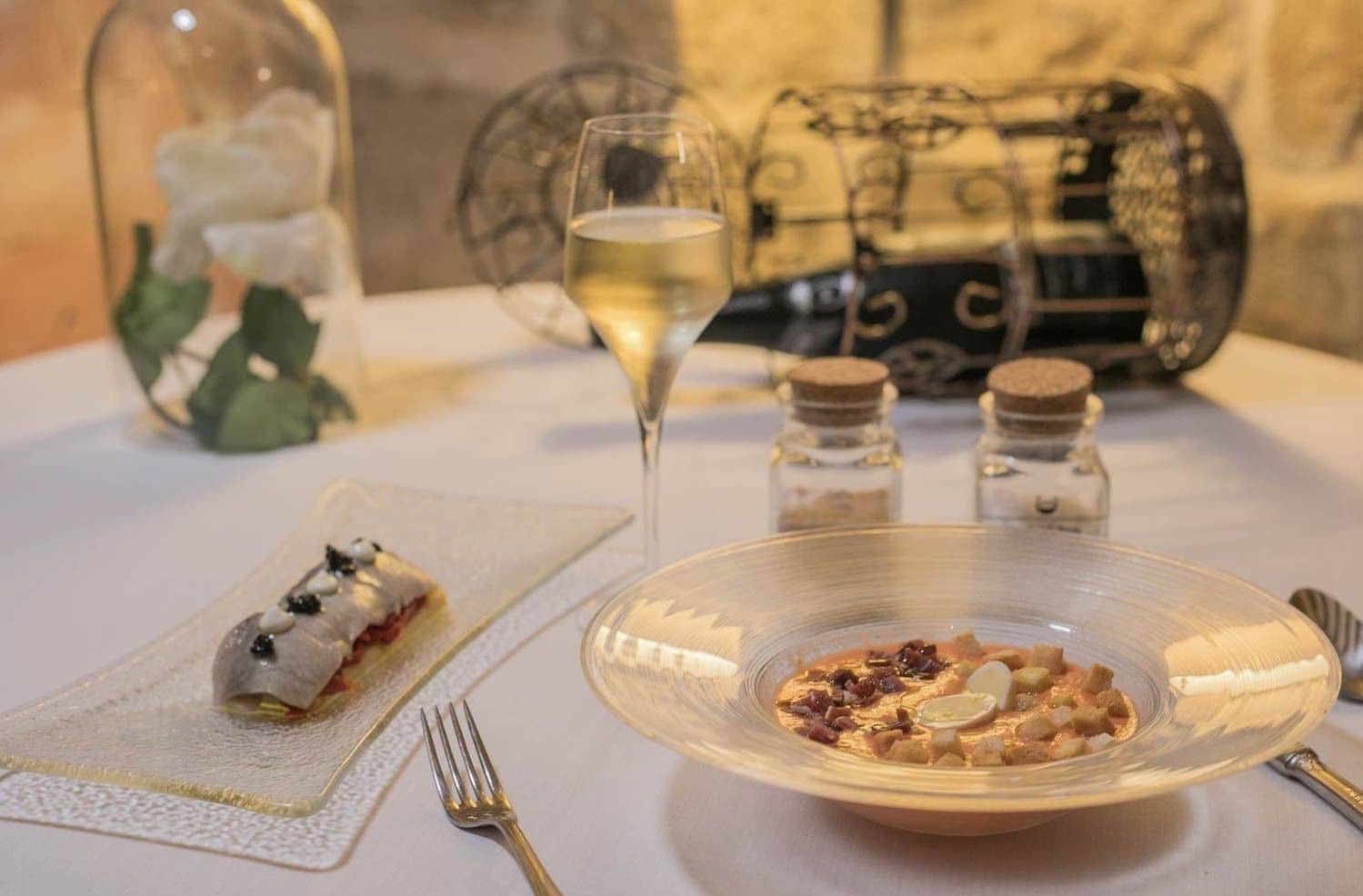 A dining table with a clear glass bowl of food, a wine glass, and a dessert plate.