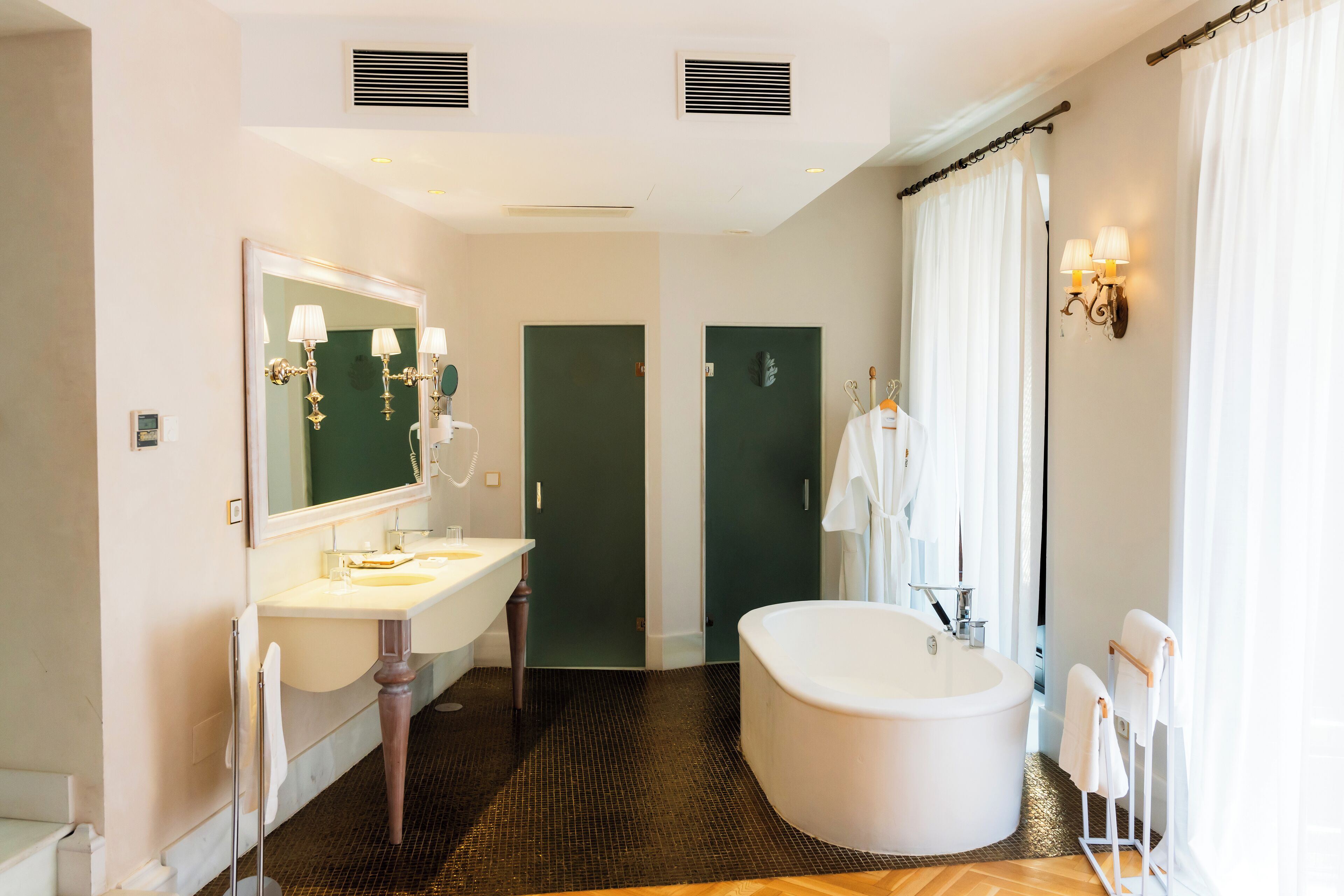 A modern bathroom with a freestanding bathtub, a large mirror, and a vanity with two sinks.
