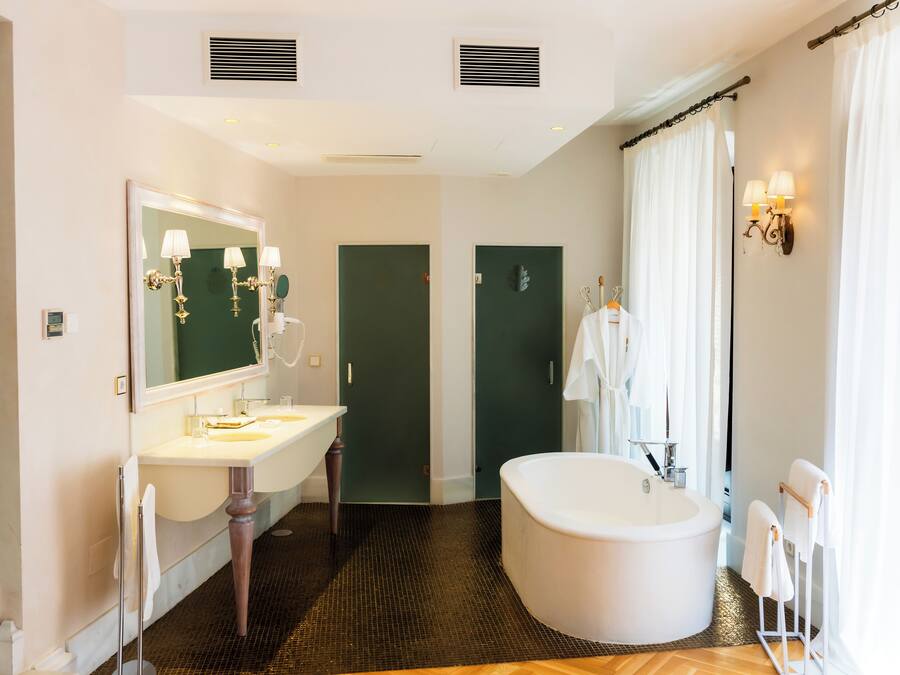 A modern bathroom with a freestanding bathtub, a large mirror, and a vanity with two sinks.