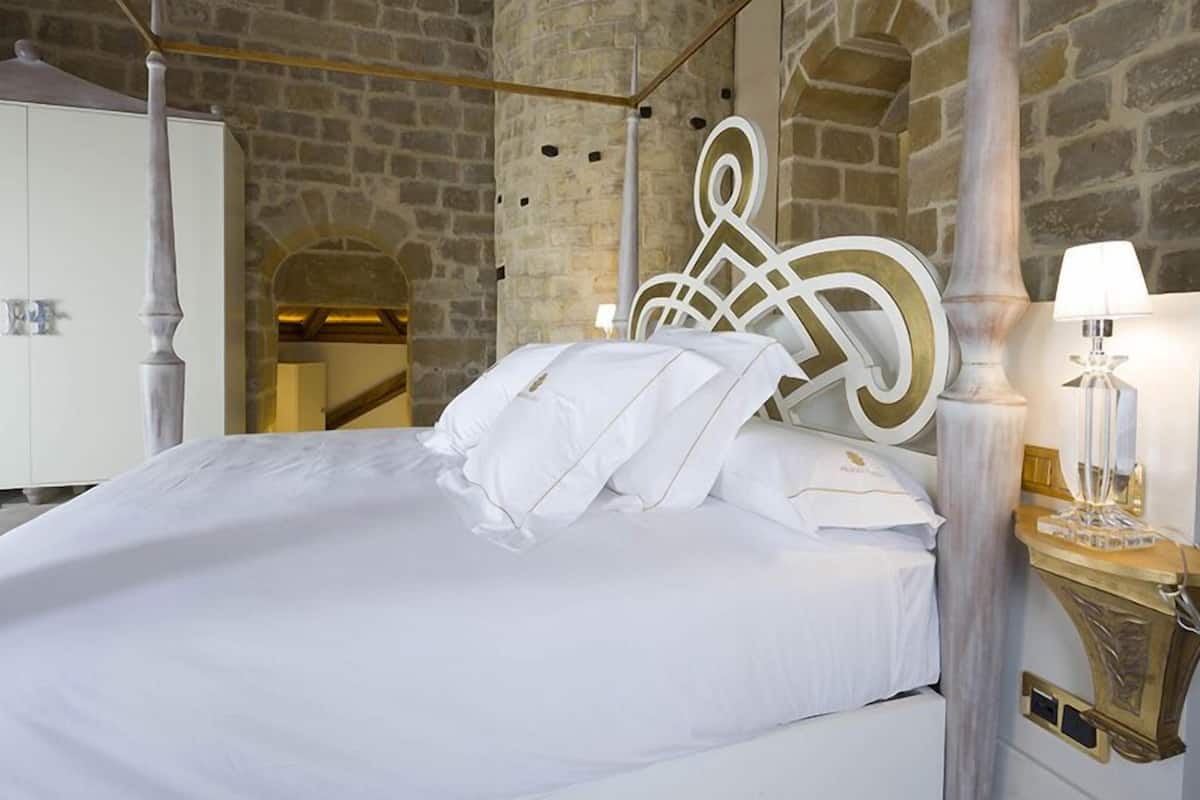 Una cama con sábanas y almohadas blancas, un armario blanco y un adorno en la pared.