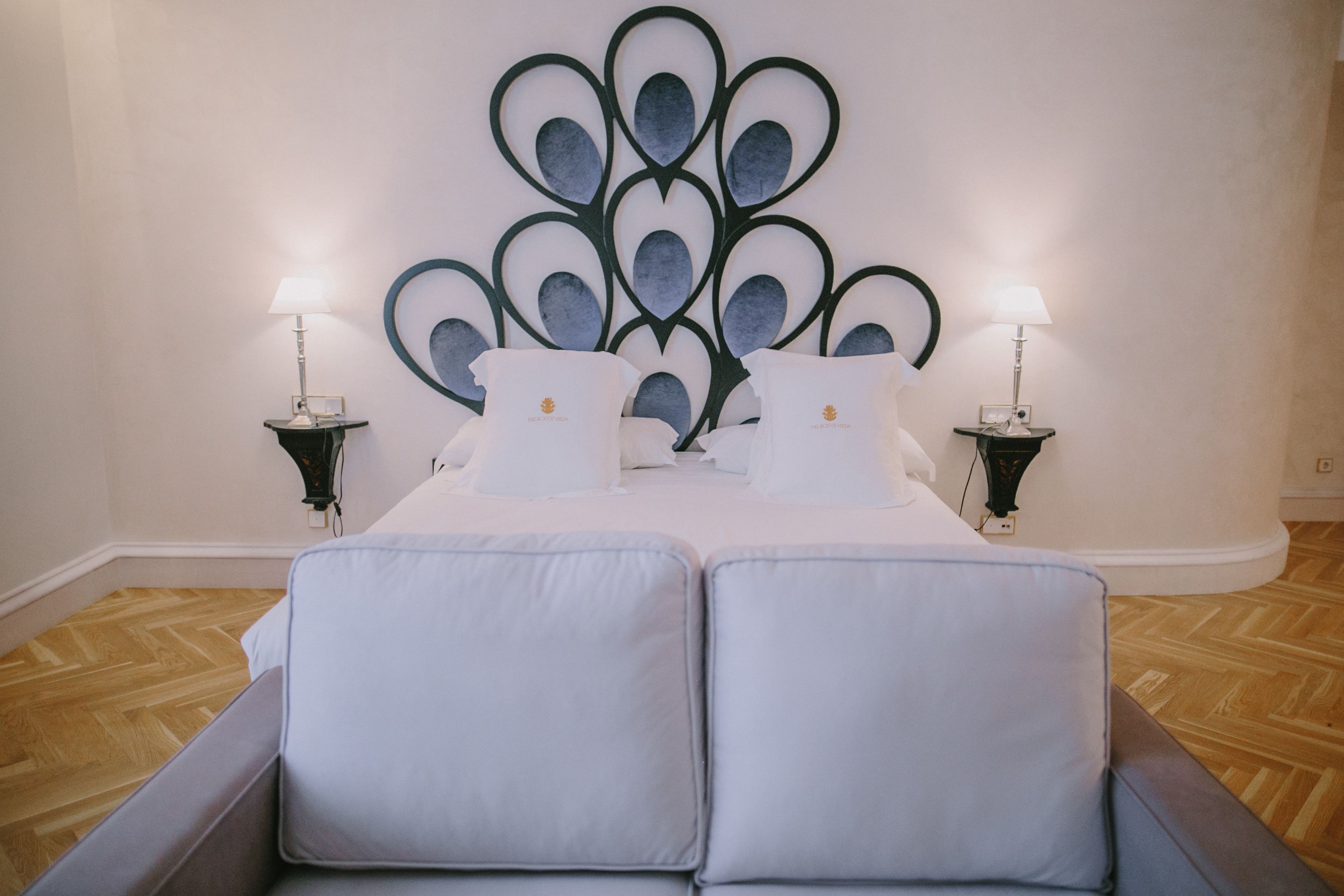 Una cama doble con ropa de cama blanca y dos mesitas de noche con lámparas.