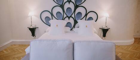 Una cama doble con ropa de cama blanca y dos mesitas de noche con lámparas.