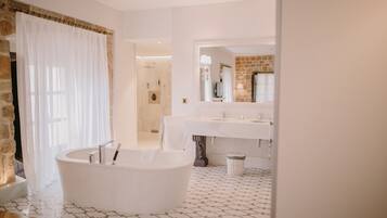 Un bany modern amb una banyera independent, un moble de bany doble i un mirall gran.