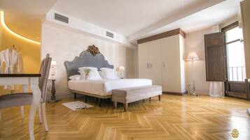A hotel room with a bed, bedside table, lamp, wardrobe, and a chair.