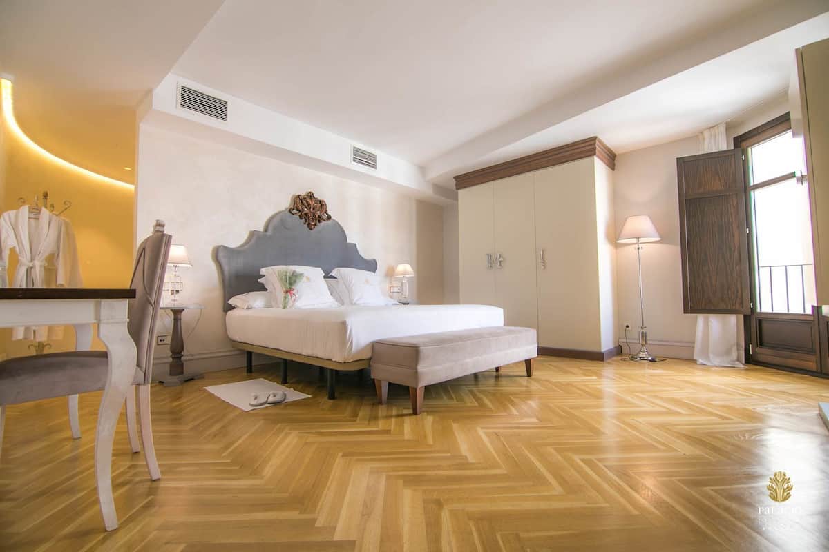 Una habitación de hotel con cama, mesita de noche, silla, armario y ventana.