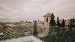 A rooftop pool with a view of a historic town, including a church tower and terracotta-tiled buildings.
