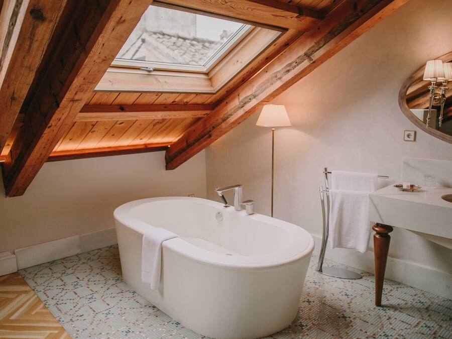 Un baño moderno con tragaluz, una bañera independiente, un tocador con espejo y un suelo de diseño geométrico.