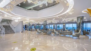 Un hall espacioso con una escalera central, zonas de estar y grandes ventanales que ofrecen vistas al exterior.