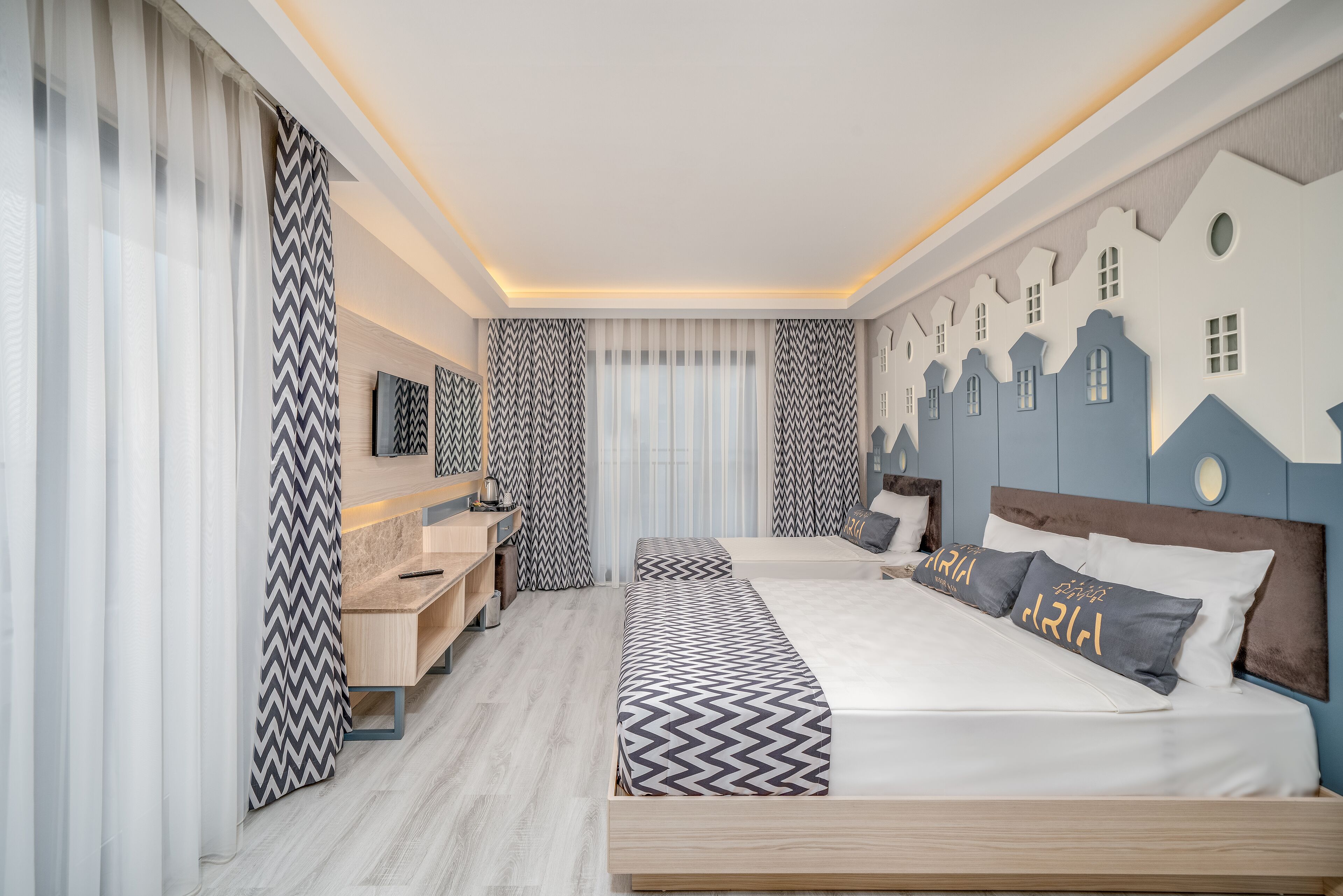A modern hotel room with a large bed, a desk, and a vanity.