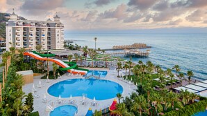 Un resort con varias piscinas, un tobogán acuático y vistas al mar.