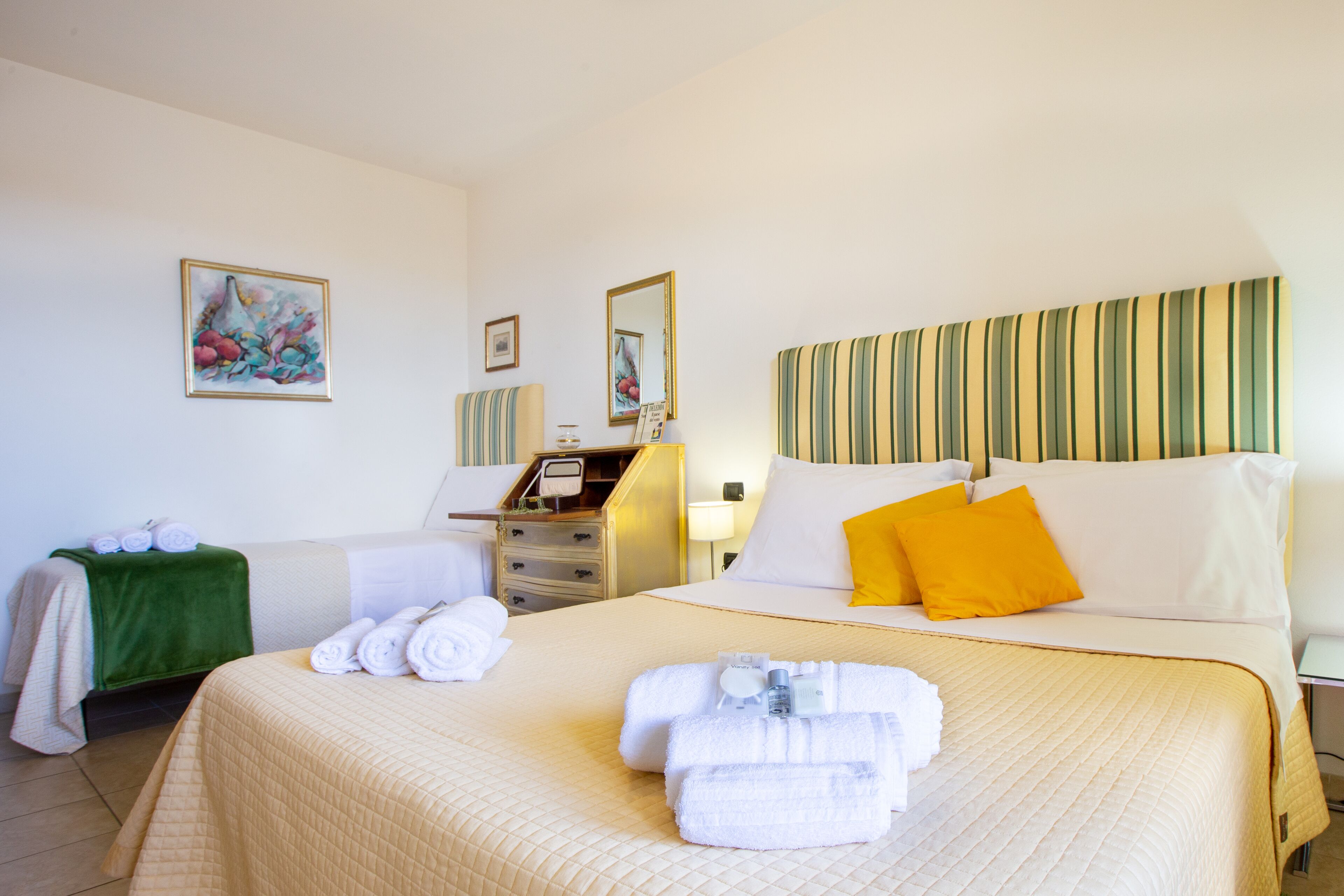 Ein Hotelzimmer mit Bett, Nachttisch, Spiegel und Bildern an den Wänden.