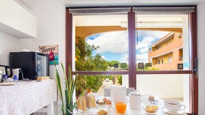 A breakfast table with a variety of food items, a coffee machine, and a view of a building through a window. - Sun&Sardinia (Monserrato)