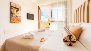 A hotel room with a bed, a painting on the wall, a television, and a view of the outdoors. - Sun&Sardinia (Monserrato)