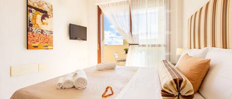A hotel room with a bed, a painting on the wall, a television, and a view of the outdoors.