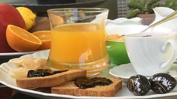 Een ontbijt bord met toast, jam, een glas sinaasappelsap en twee chocolade snoepjes.