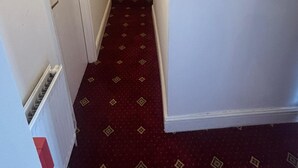 A narrow hallway with a red carpet and white walls. - Golden Star Hotel (London)