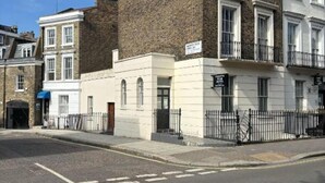 A two-story building with a white facade and a brown brick section. - Golden Star Hotel (London)