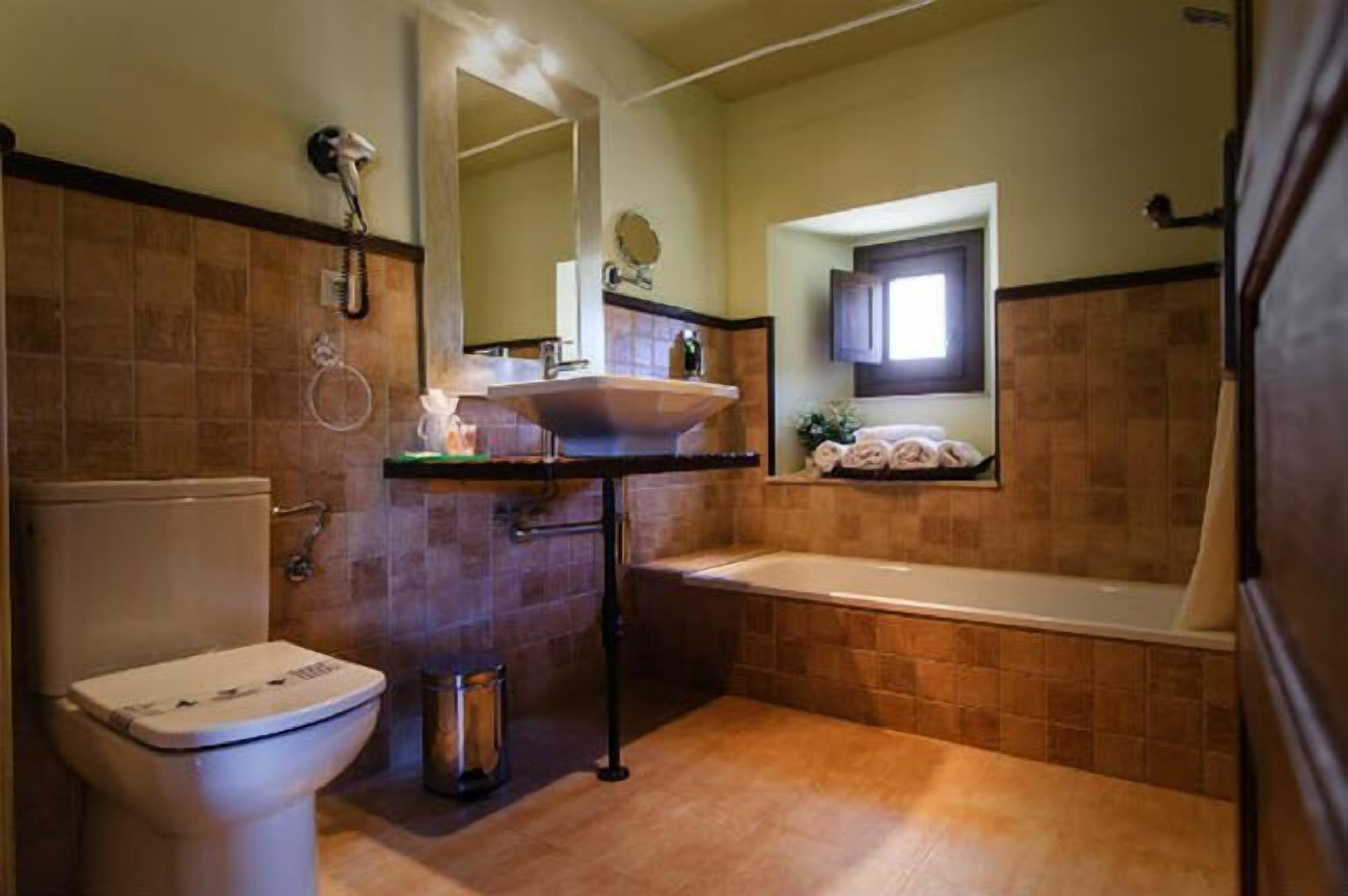 Et badeværelse med toilet, vask og badekar.