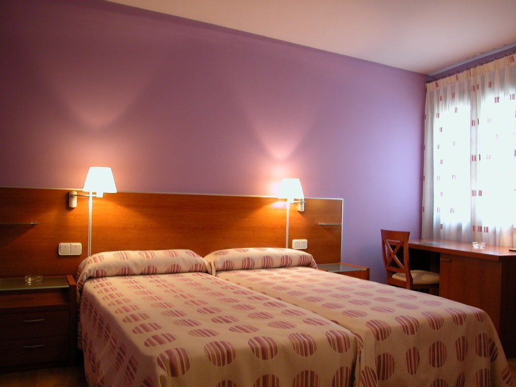 Een hotelkamer met twee bedden, een bureau en een stoel.