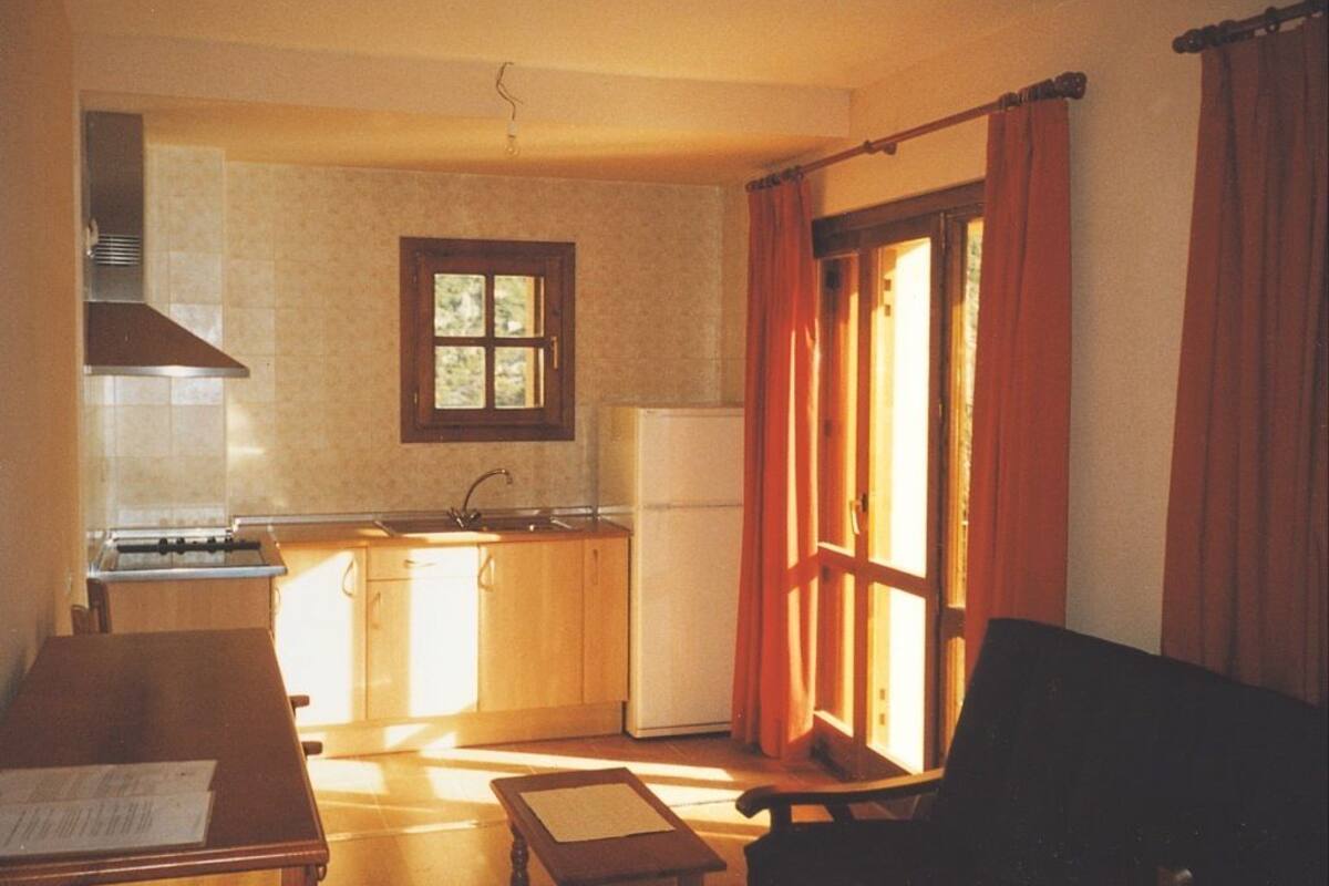A compact kitchen with a window, a dining table, and a chair.