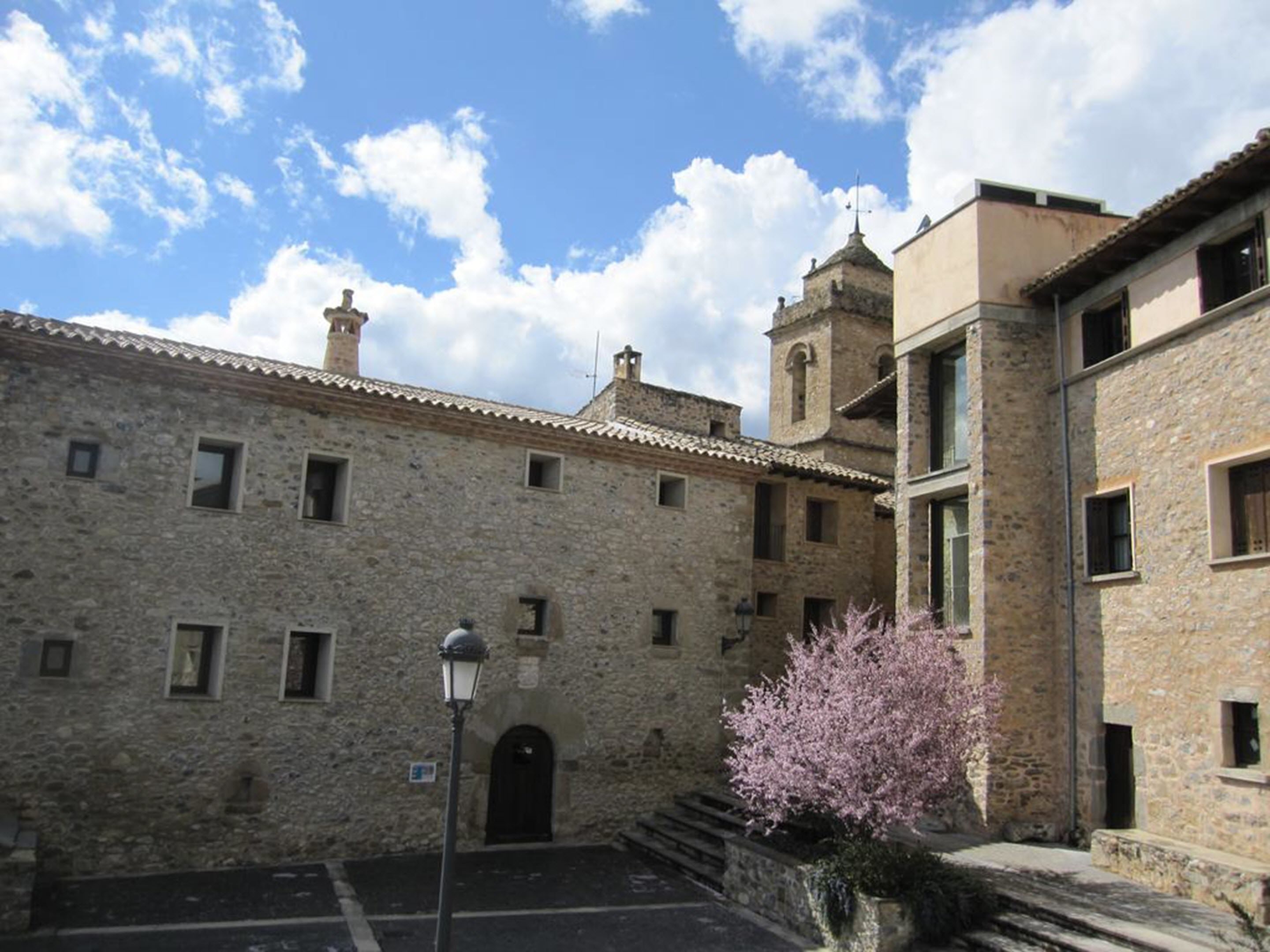 Un edificio de piedra con una torre de campana, una entrada pequeña y un farol.