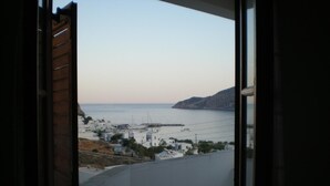A balcony with a view of a coastal town, buildings, and a distant island. - Froudi (Sifnos)
