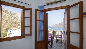 A balcony with stone flooring, wooden doors, and a view of the sea and mountains. - Froudi (Sifnos)